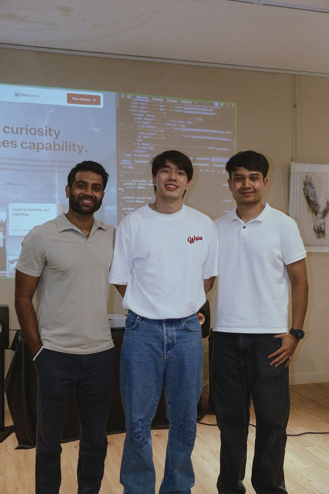 Three members of the Metacamp team in front of the projected line Where curiosity becomes capability